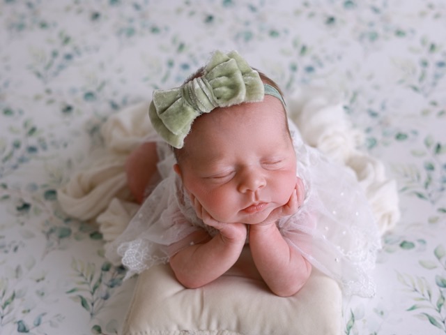 Sleeping newborn with a bow headband, from a baby photography session