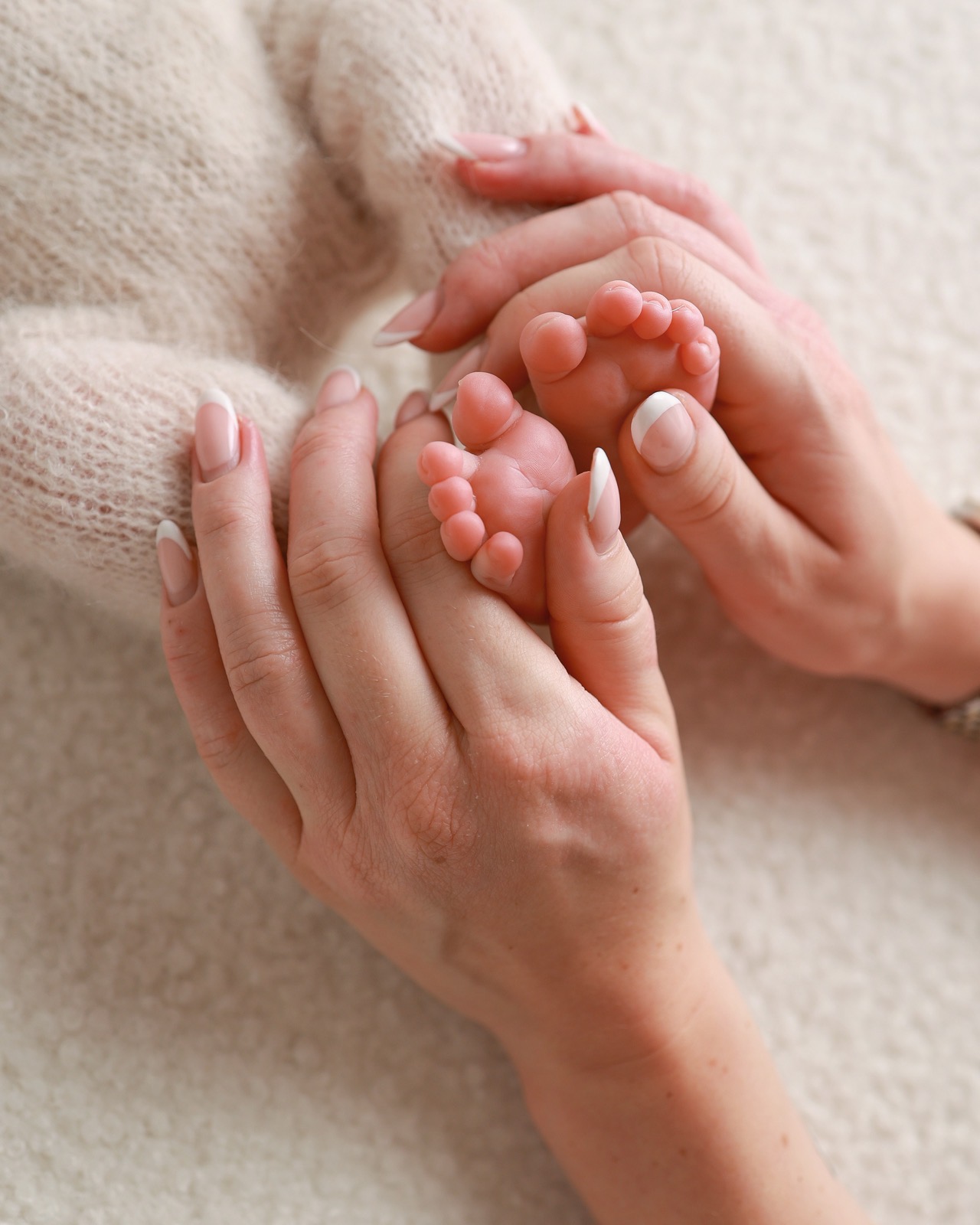 Close-up of a parent's hands cradling their newborn's two tiny feet together