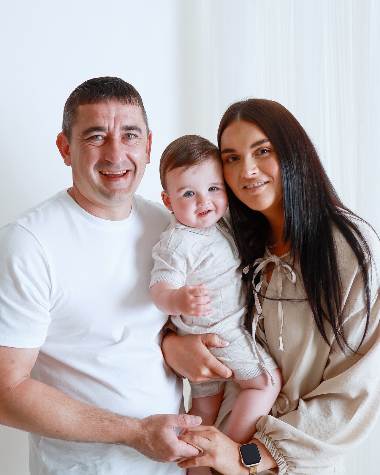 Close-up of a family of three, dad, toddler boy and mum with their heads close together, smiling