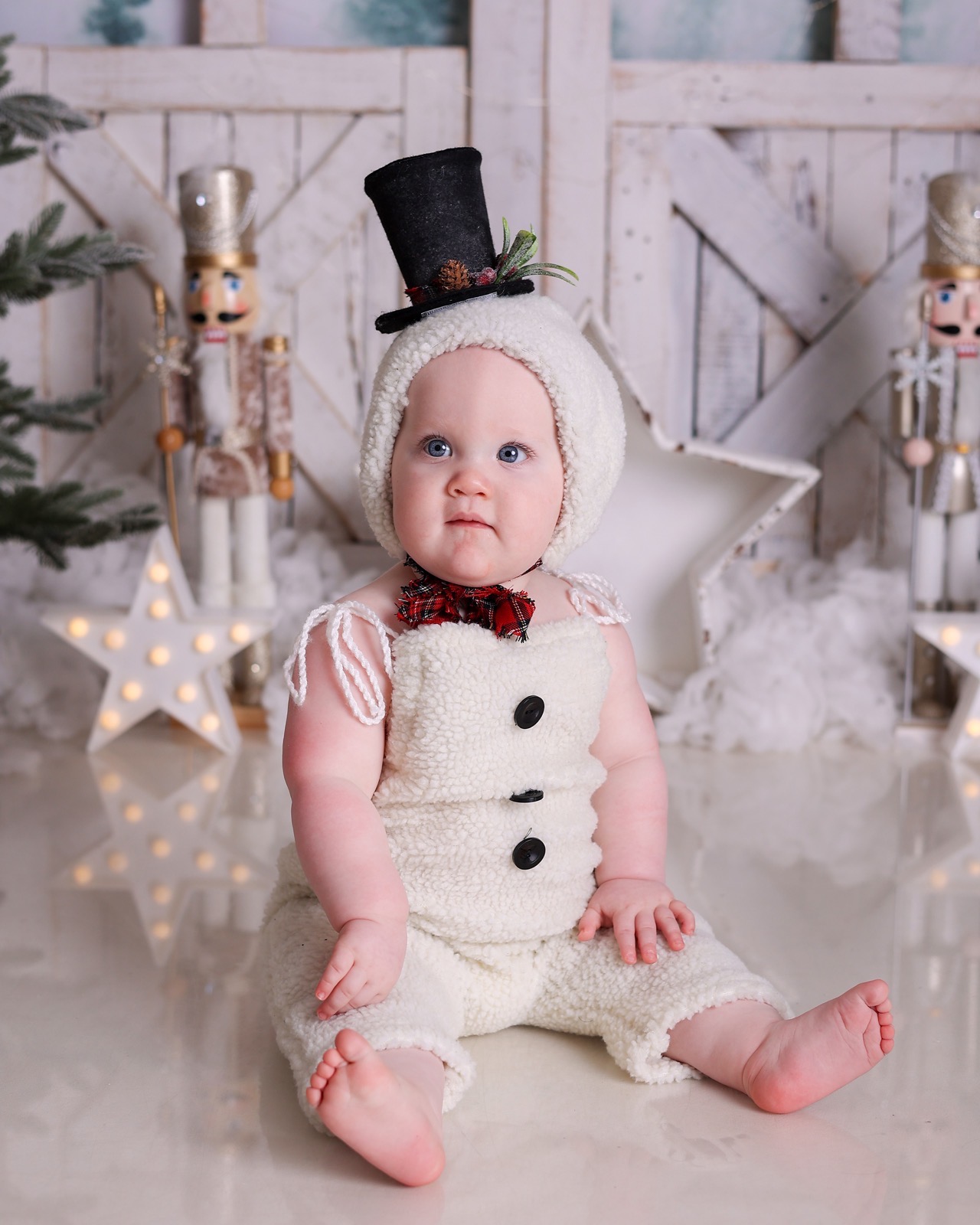 Close-up of a baby in a snowman costume with a black top hat and tartan bow tie