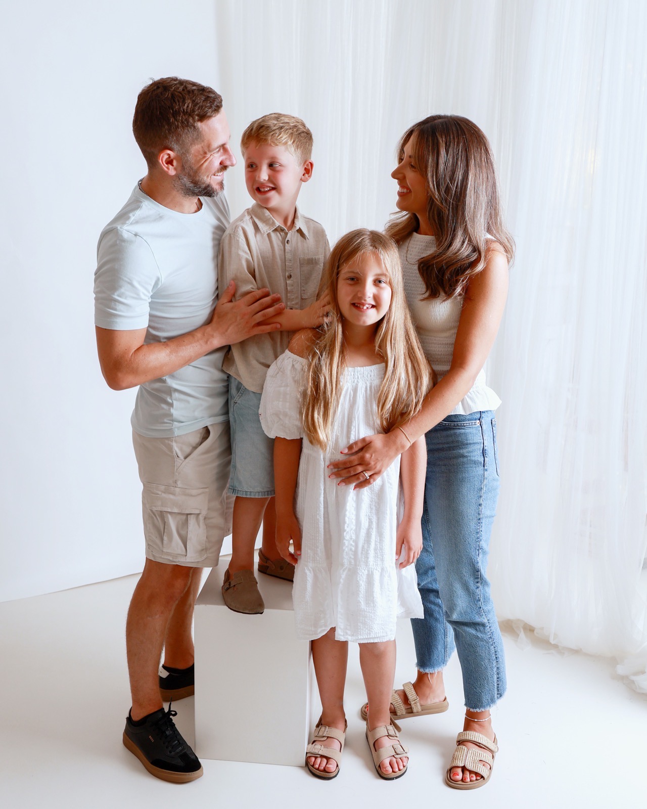 Family of four in another candid moment, smiling and looking between each other