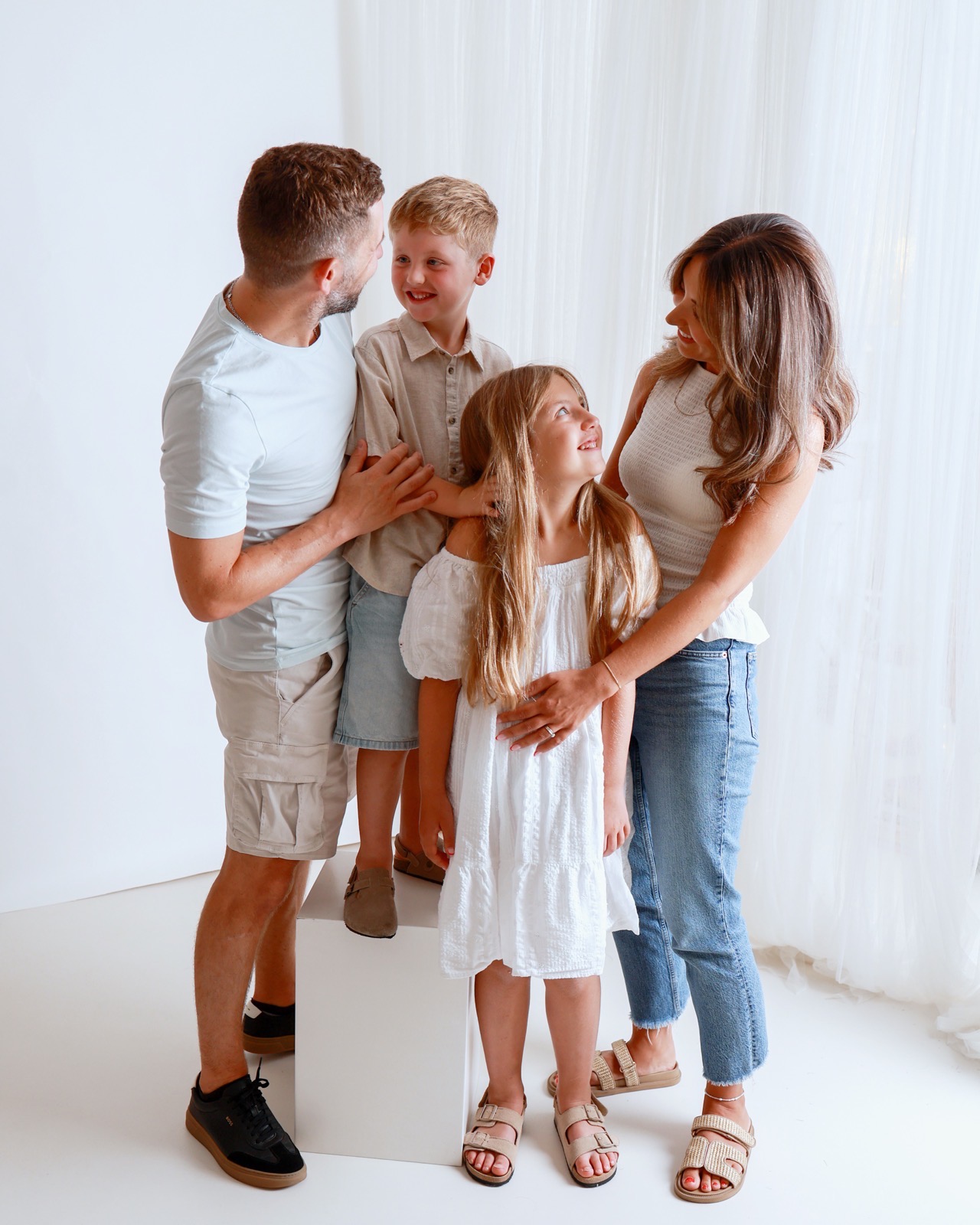 Family of four in a closer candid moment, dad and son face to face while the girl looks up