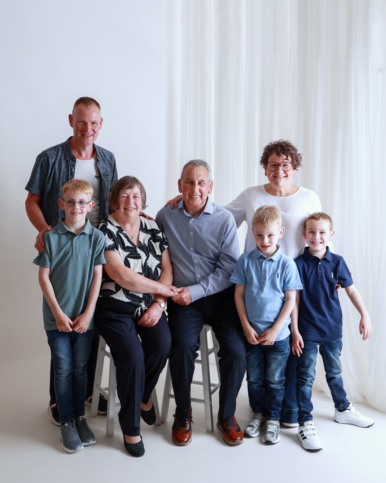 Extended family of seven, grandparents seated with their son, daughter, grandsons and a baby girl