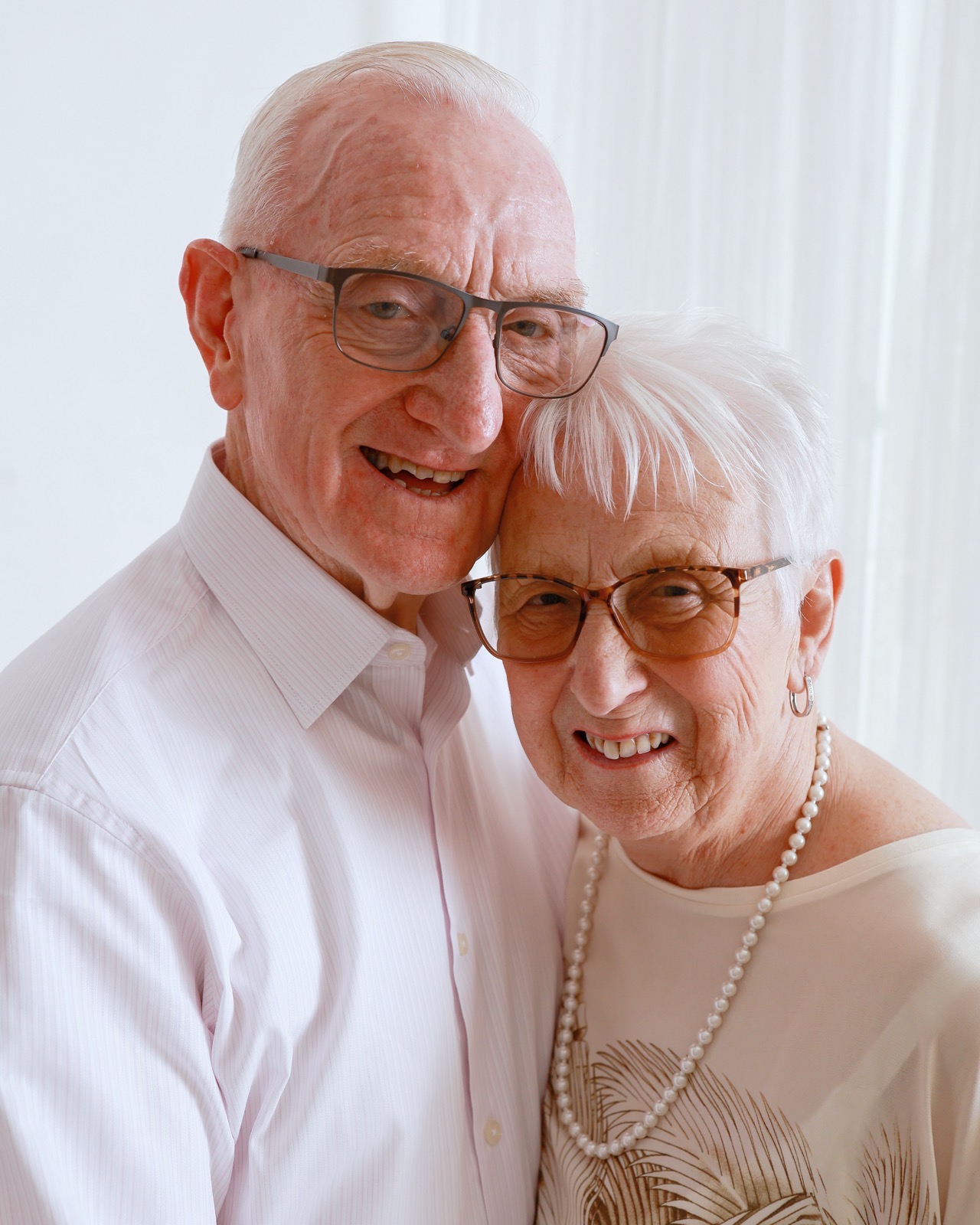 Close-up portrait of an elderly couple, foreheads together, both smiling
