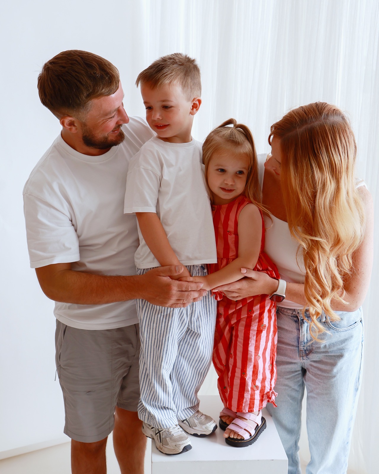 Family of four in a candid moment, parents smiling down at their children