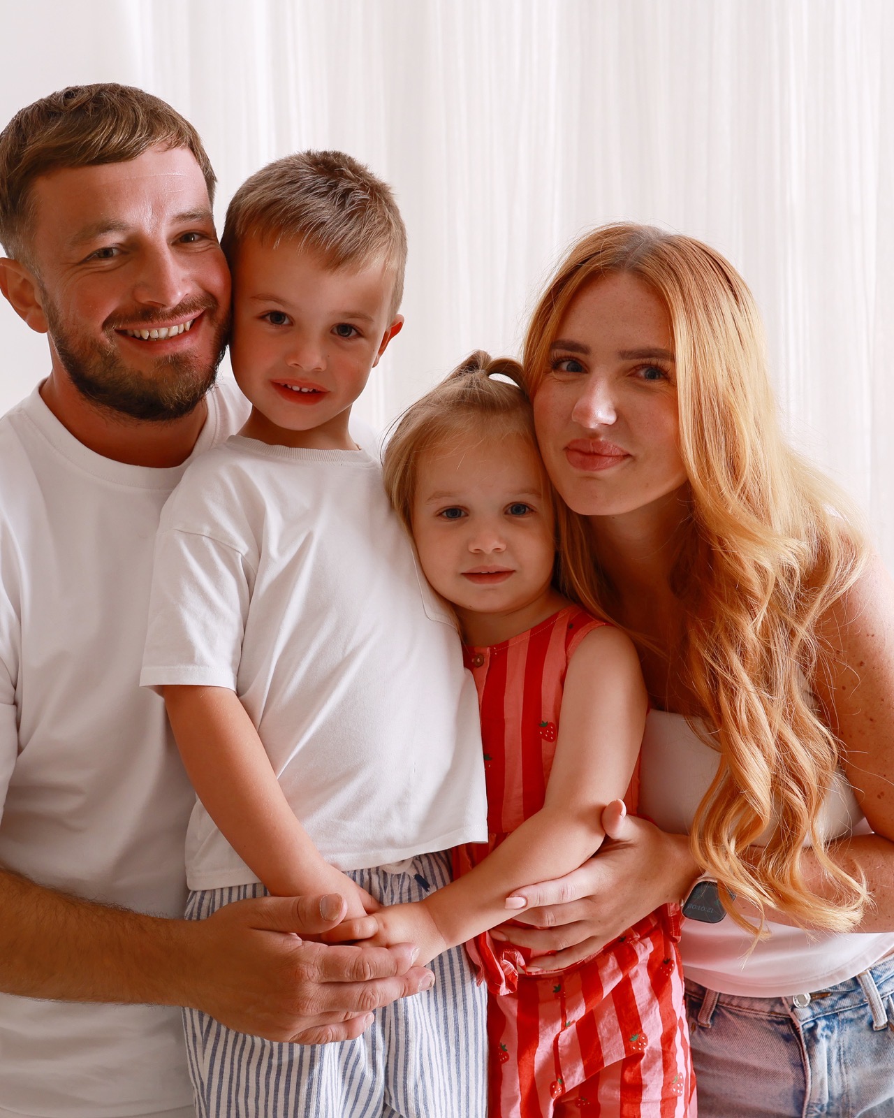 Family of four in a close portrait, children in front, parents smiling behind