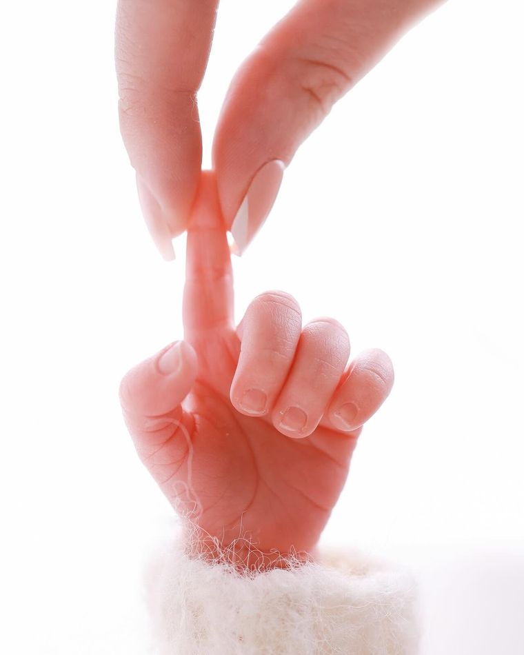 Close-up of a parent's hand holding a newborn baby's tiny hand