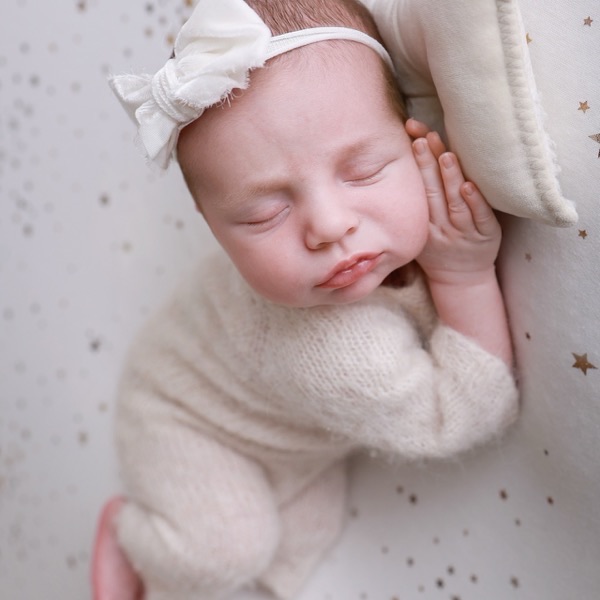 Newborn asleep with hand resting near cheek, from the same session