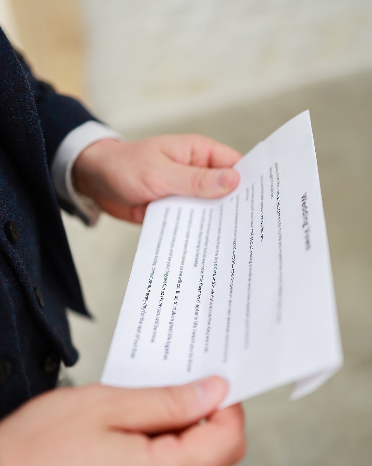 Close-up of hands holding a printed sheet of wedding vows