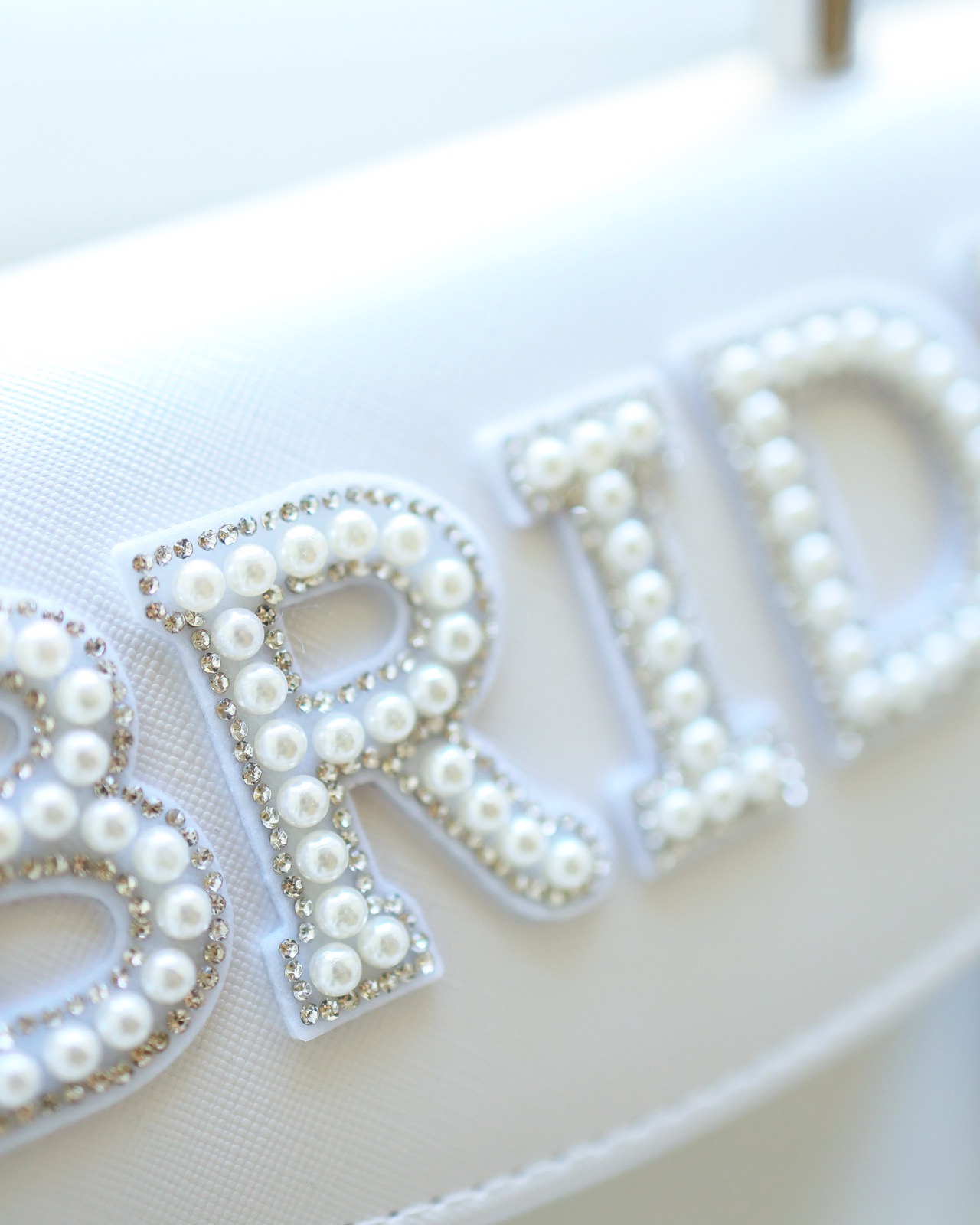 White bridal shoes with 'BRIDE' spelled out in pearl and crystal letters on the soles