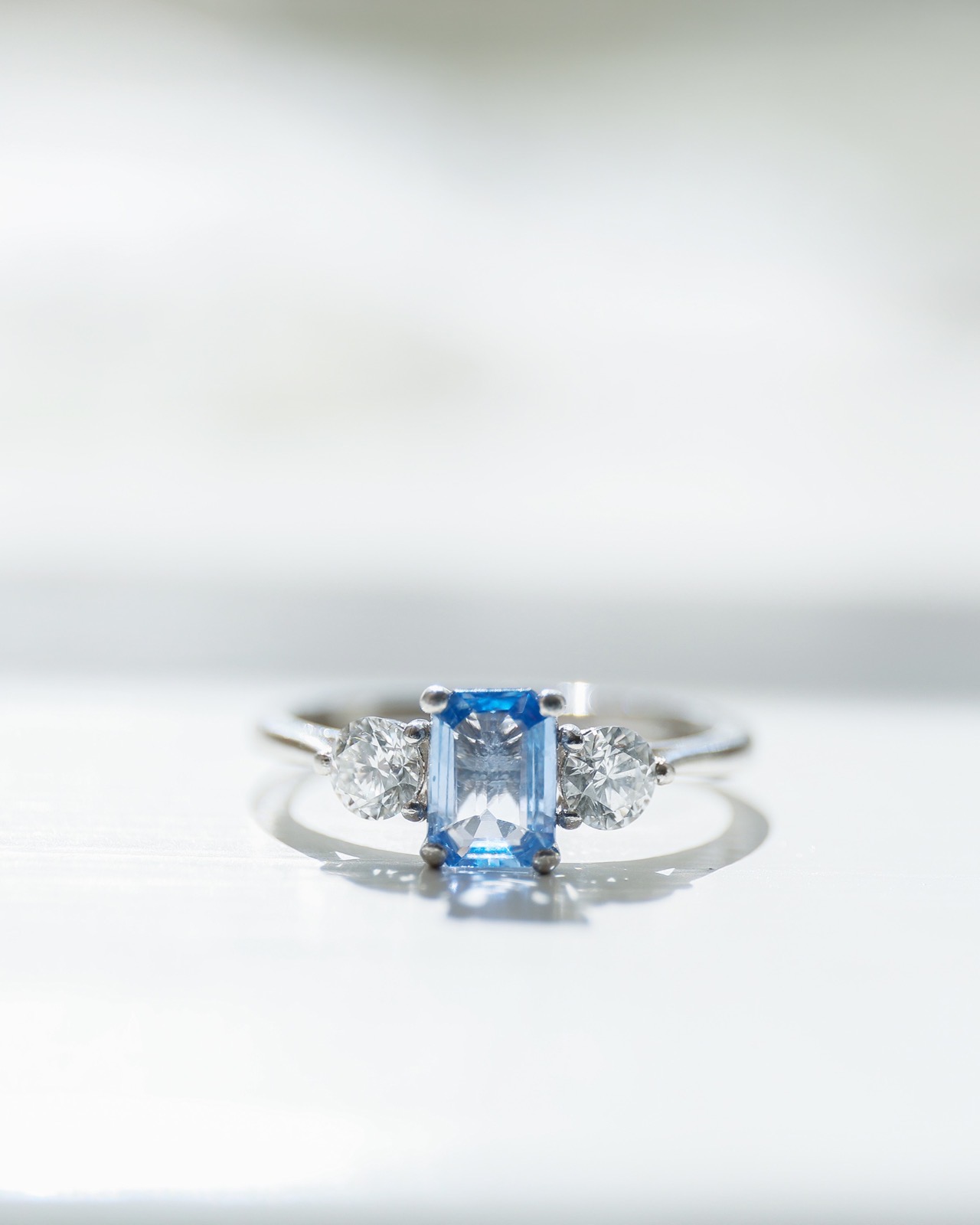 Close-up of a sapphire and diamond engagement ring against a soft white background