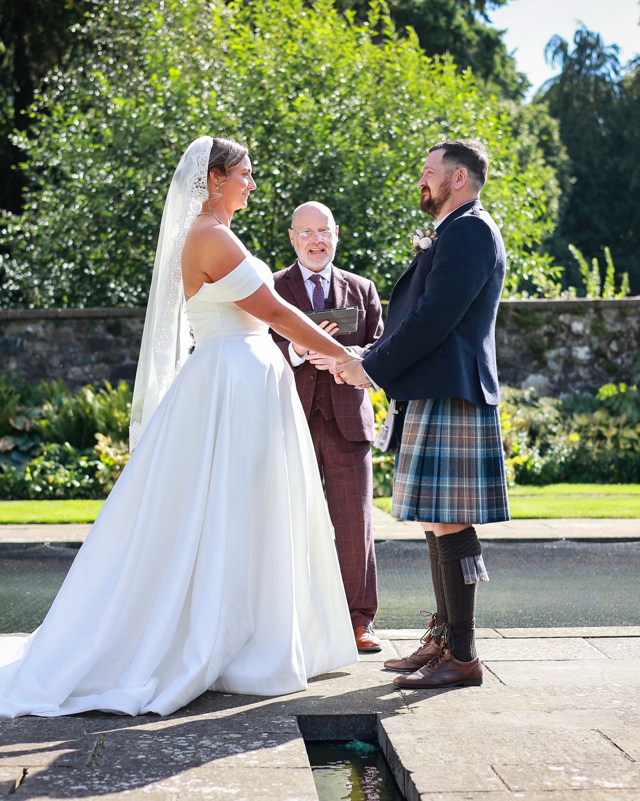 Bride and groom holding hands during their vows as the celebrant reads