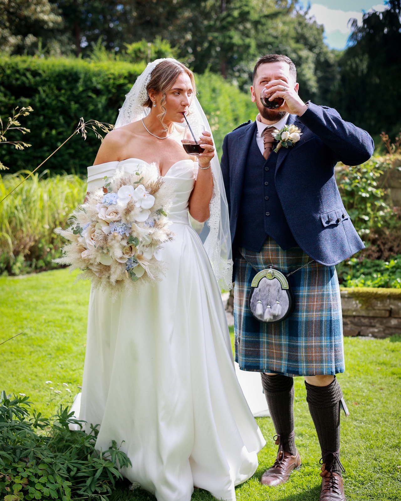 Bride and groom sharing a drink together outdoors after the ceremony, groom in a kilt and sporran