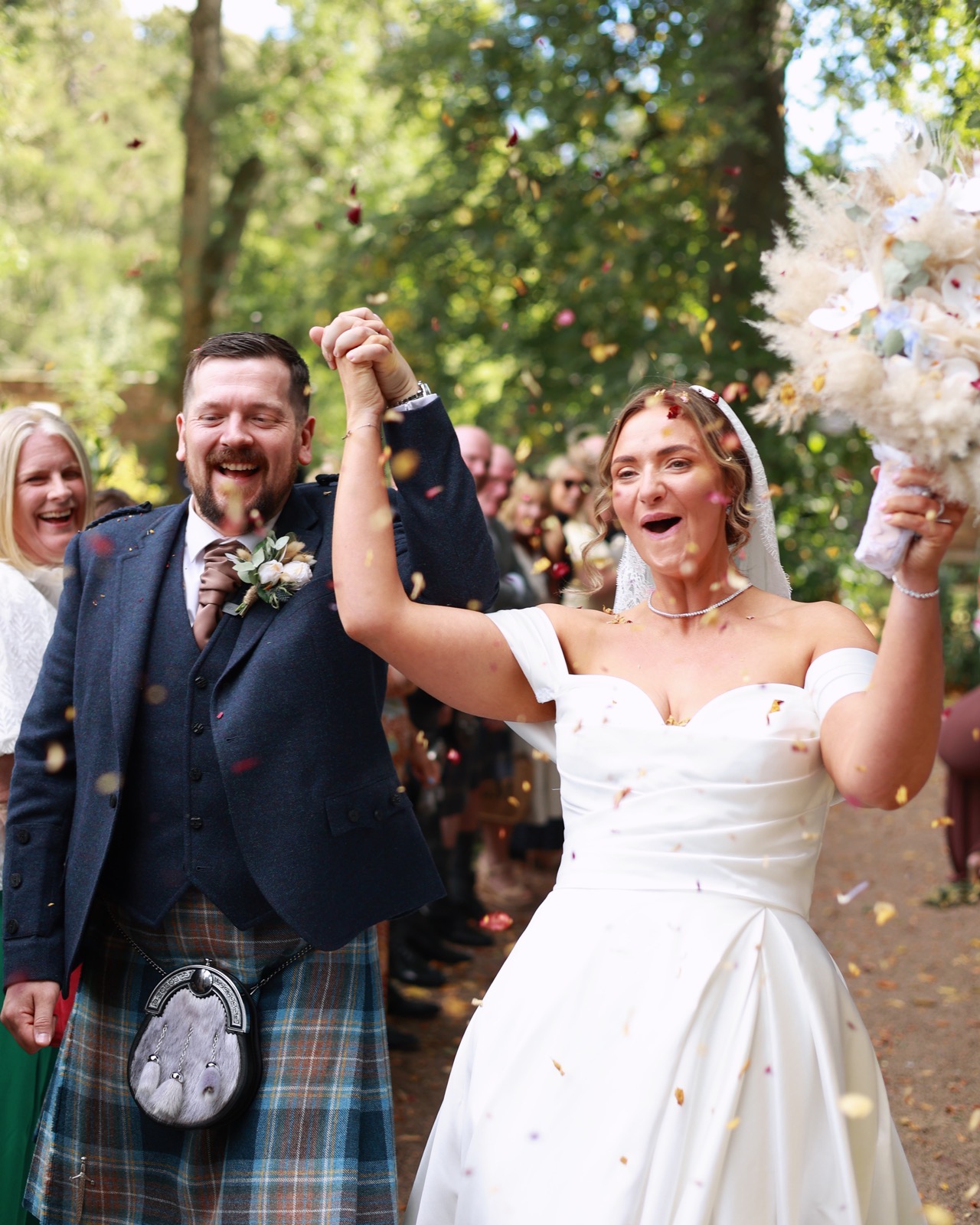 Close-up of the bride and groom laughing amid a colourful confetti shower