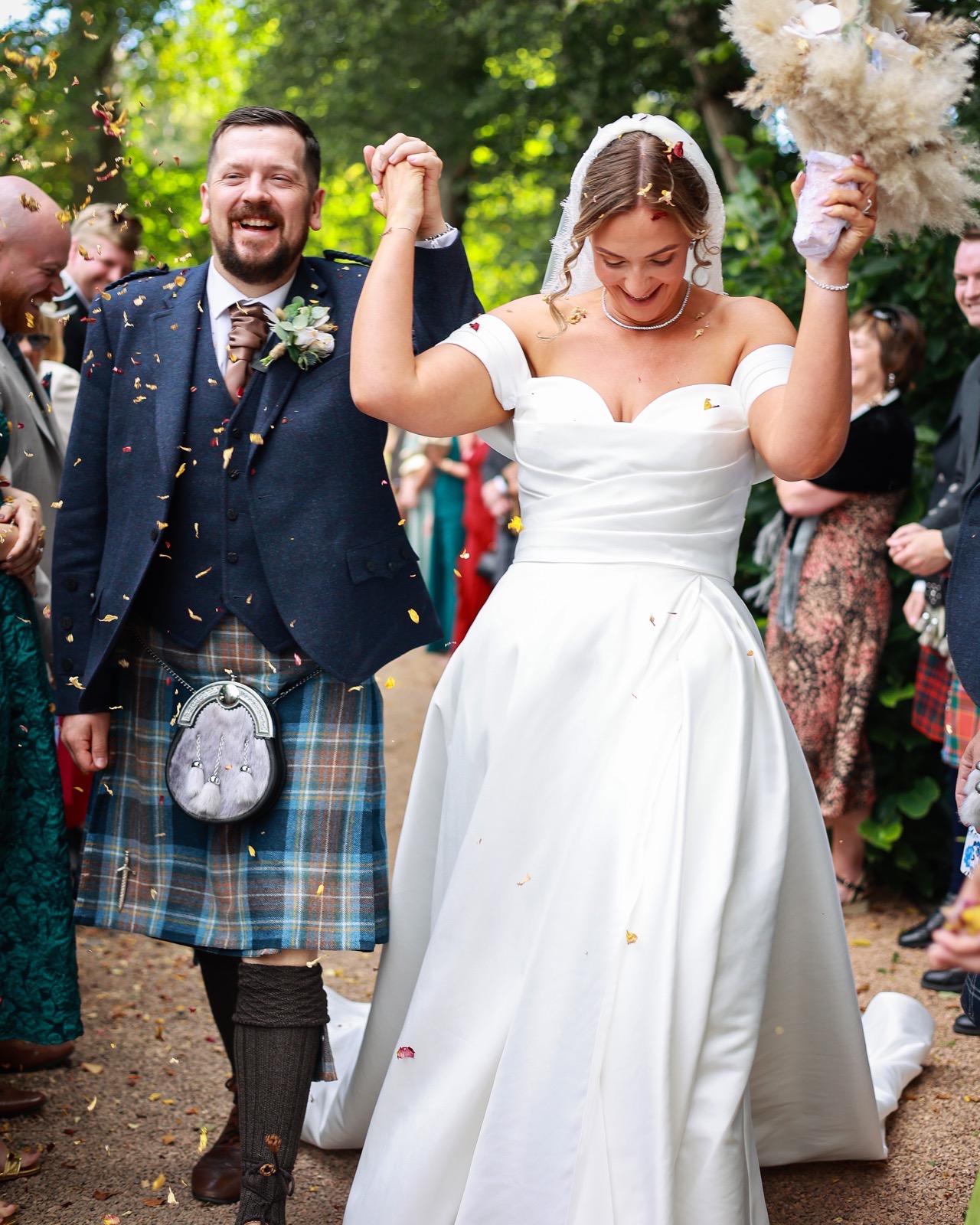 Bride and groom laughing joyfully mid-confetti, close-up portrait