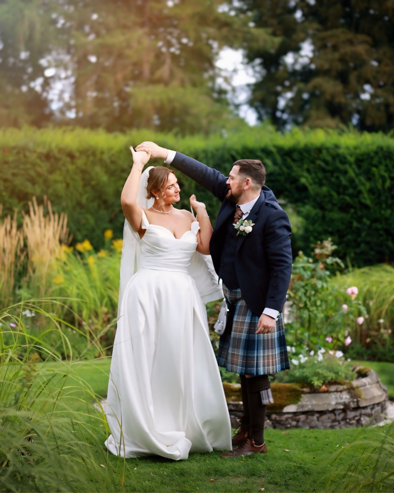 Groom twirling the bride under his raised arm in the garden