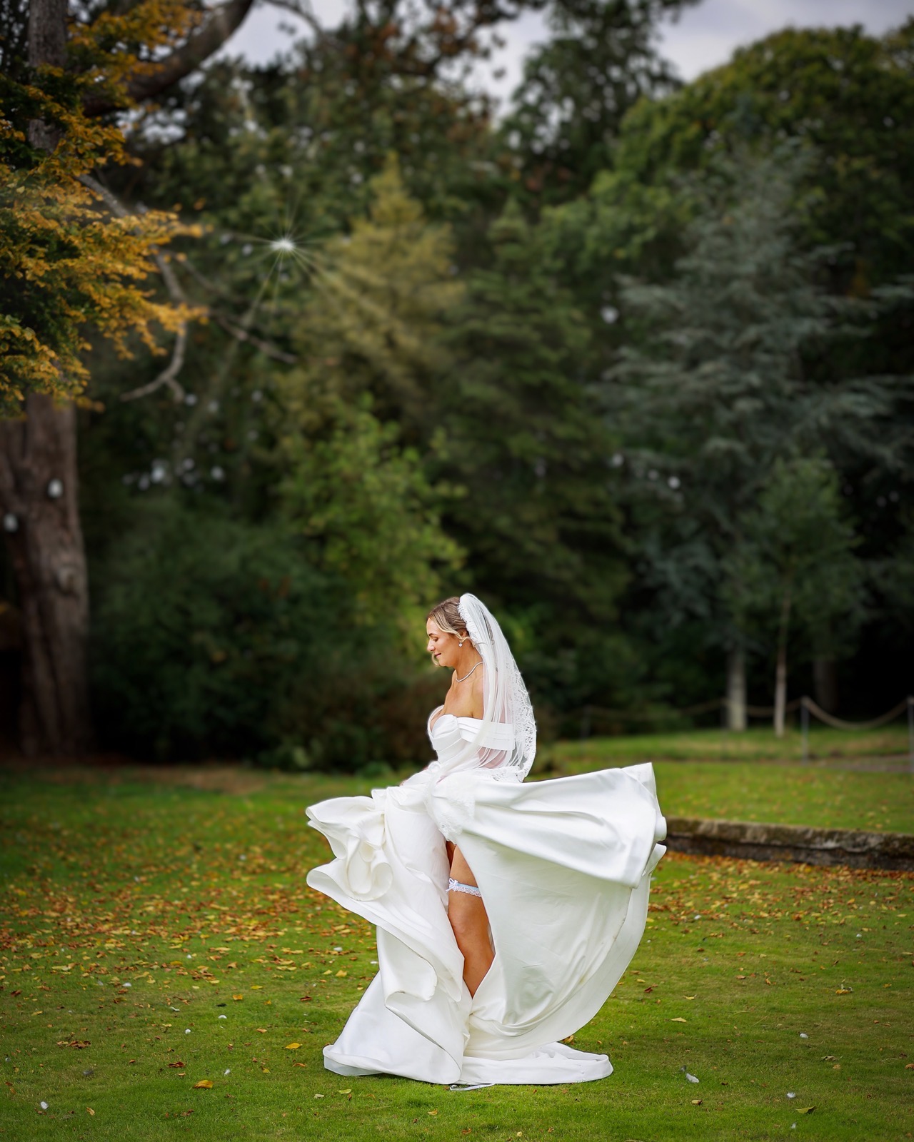 Bride twirling her wedding dress skirt with her garter visible, sun rays in the background