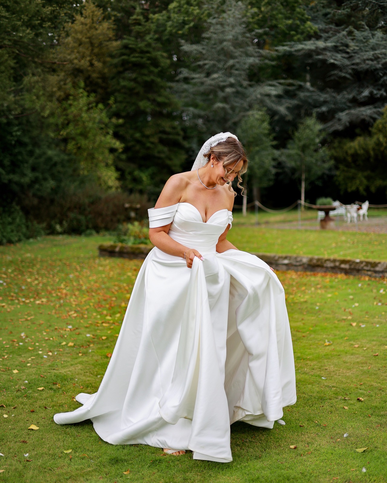 Bride holding up the sides of her dress skirt, laughing and looking down as she walks